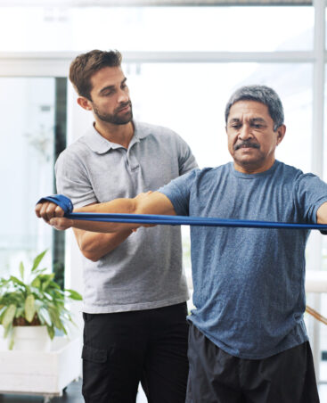 Physiotherapy, training and band with old man and doctor for stretching, rehabilitation and injury. Medical, healing and healthcare with physiotherapist and patient for consulting, help and fitness.