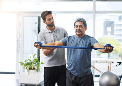 Physiotherapy, training and band with old man and doctor for stretching, rehabilitation and injury. Medical, healing and healthcare with physiotherapist and patient for consulting, help and fitness.